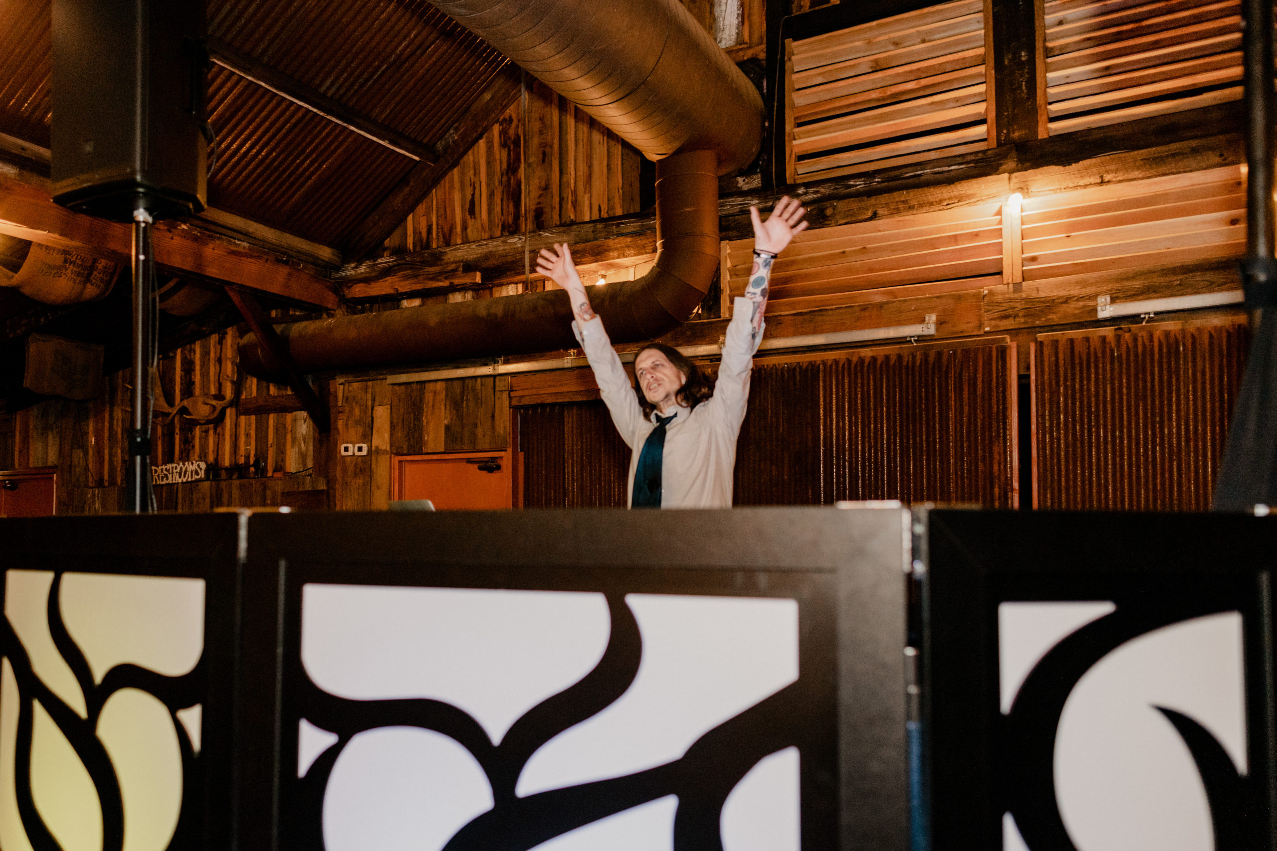 DJ with hands up in the air at a DJ Booth
