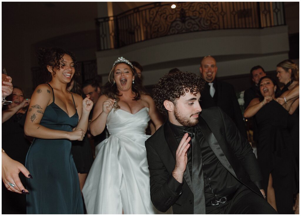 Guest dancing at wedding with bride cheering in the background. 
