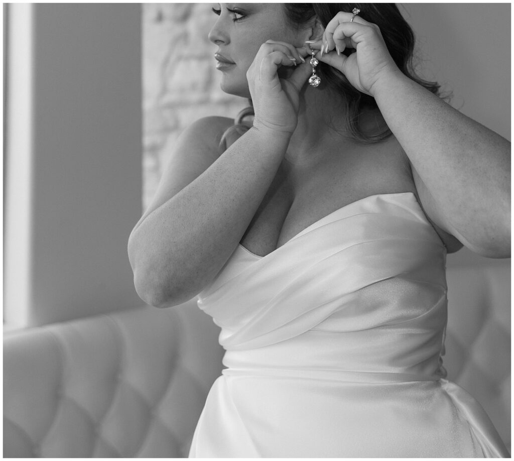 Bride in strapless wedding gown putting on earrings
