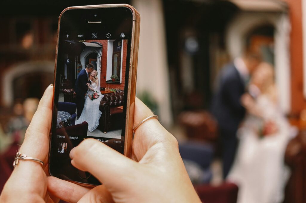 wedding content creator getting video of bride and groom with cellphone