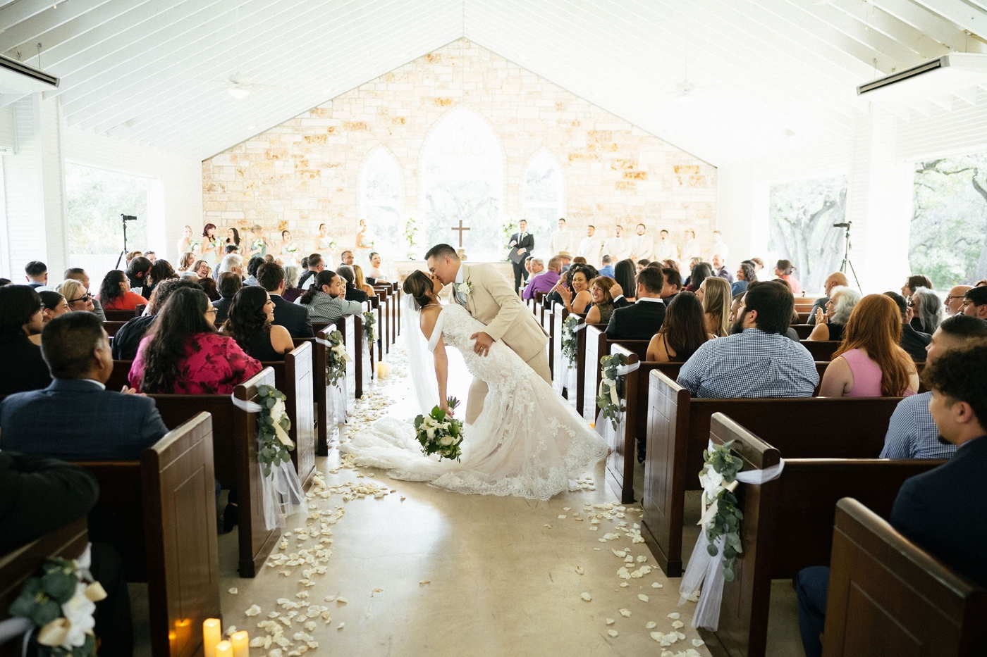 Groom dipping bride during a kiss half way down wedding ceremony aisle 